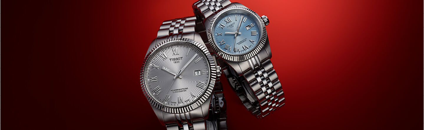 Two Tissot watches on a red background.